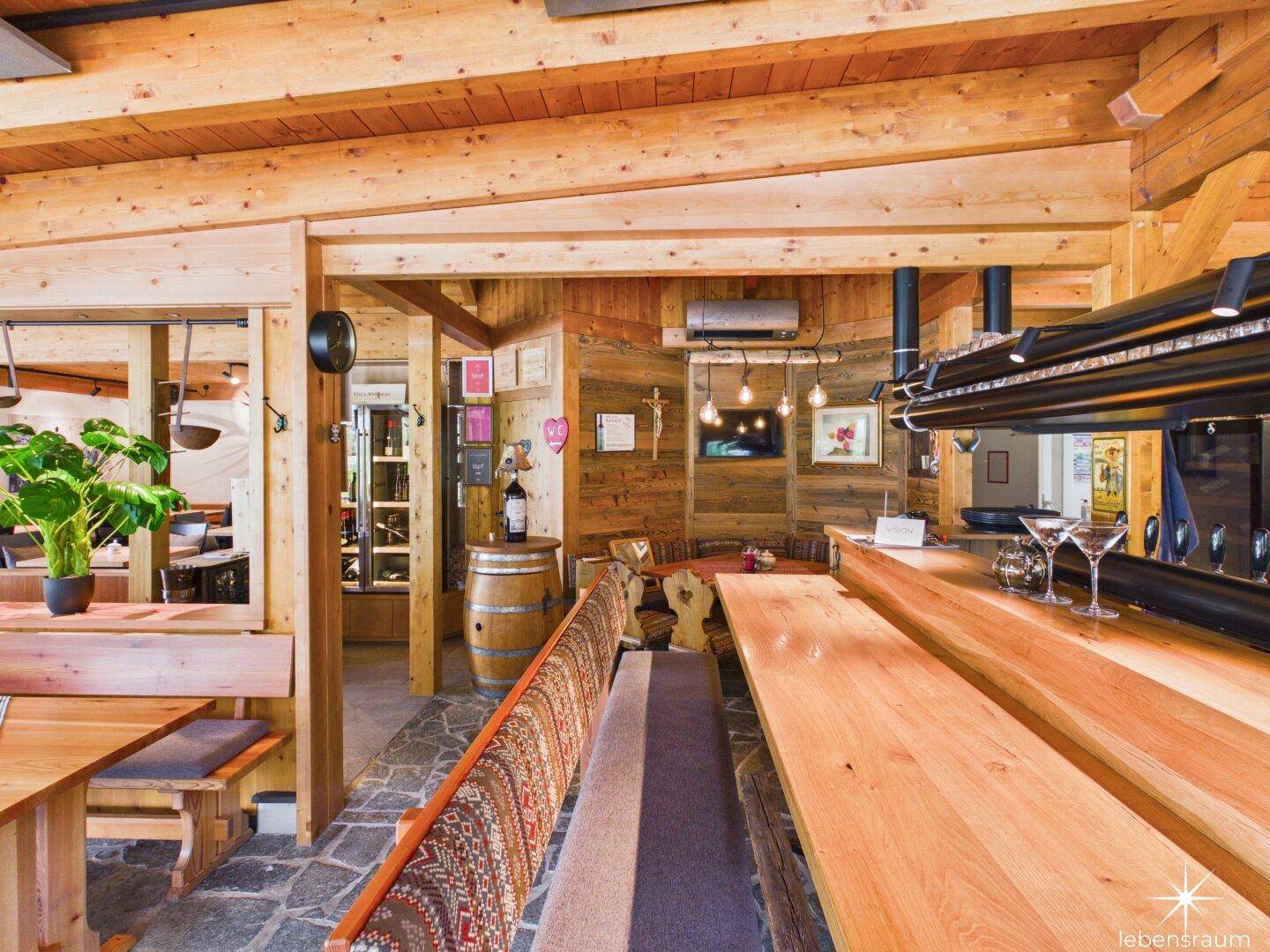 Rustikale Bar mit Holztresen, Steinboden und traditioneller Einrichtung in einem Restaurant.