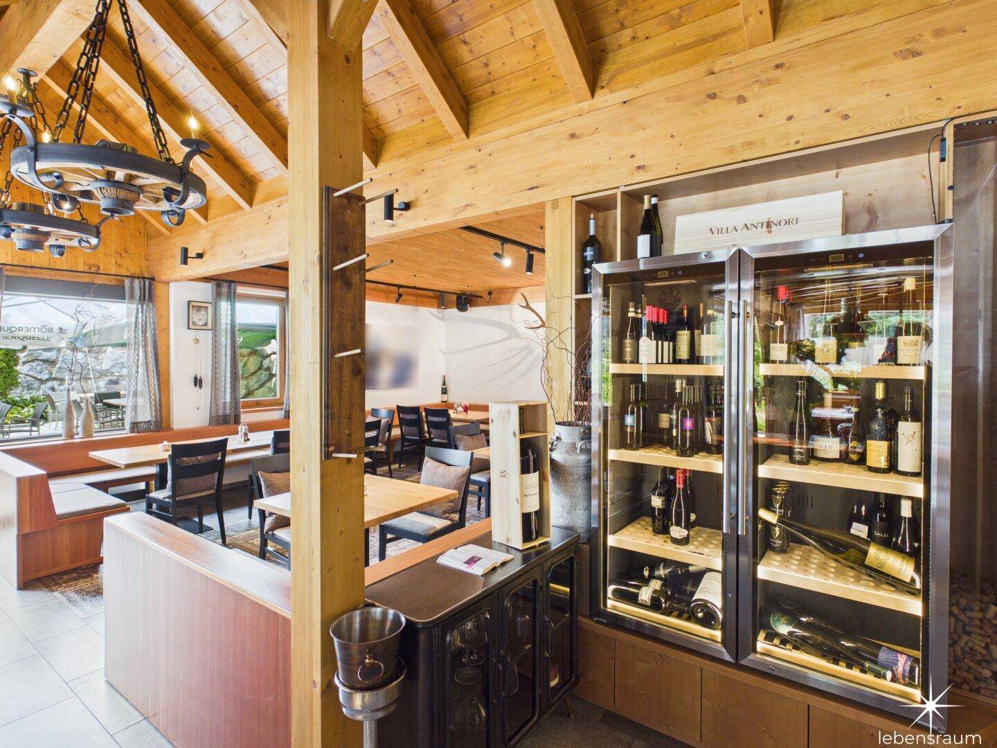 Restaurantbereich mit Holzbalken, Weinkühlschränken und traditionellen Tischen und Bänken.
