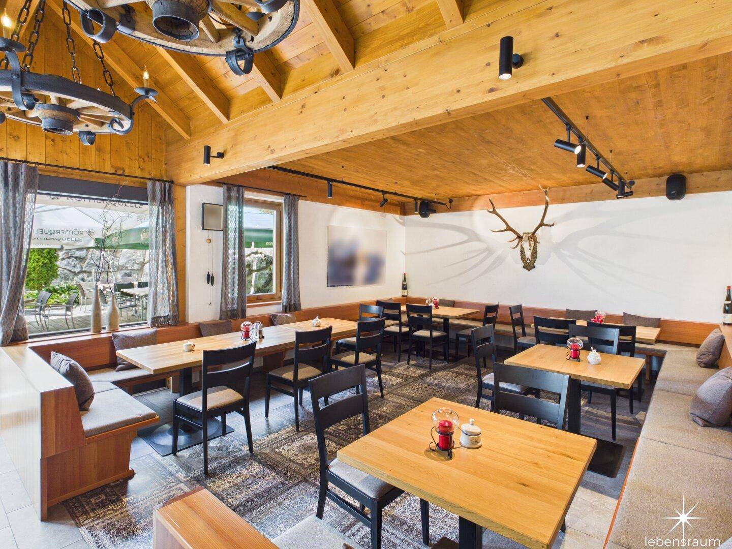 Geräumiger Restaurantbereich mit Holzbalken, großen Fenstern und traditionellen Sitzgelegenheiten.