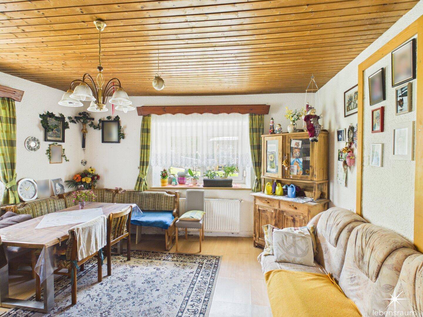 Gemütlicher Wohn-Essbereich mit Holztäfelung an der Decke und traditionellen Möbeln.