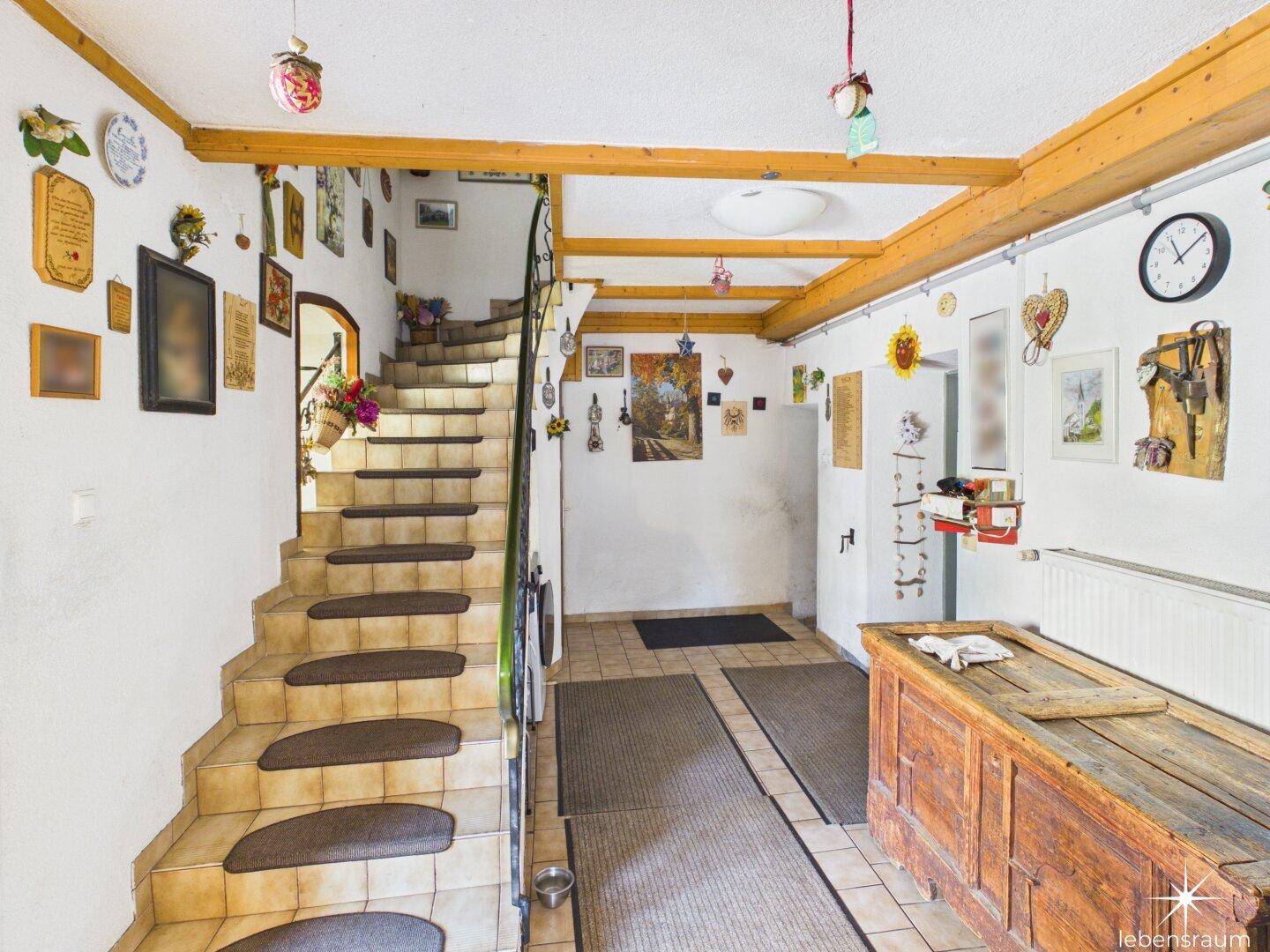 Geräumiger Flur mit gefliestem Boden, Holztreppe und rustikalen Dekorationen.