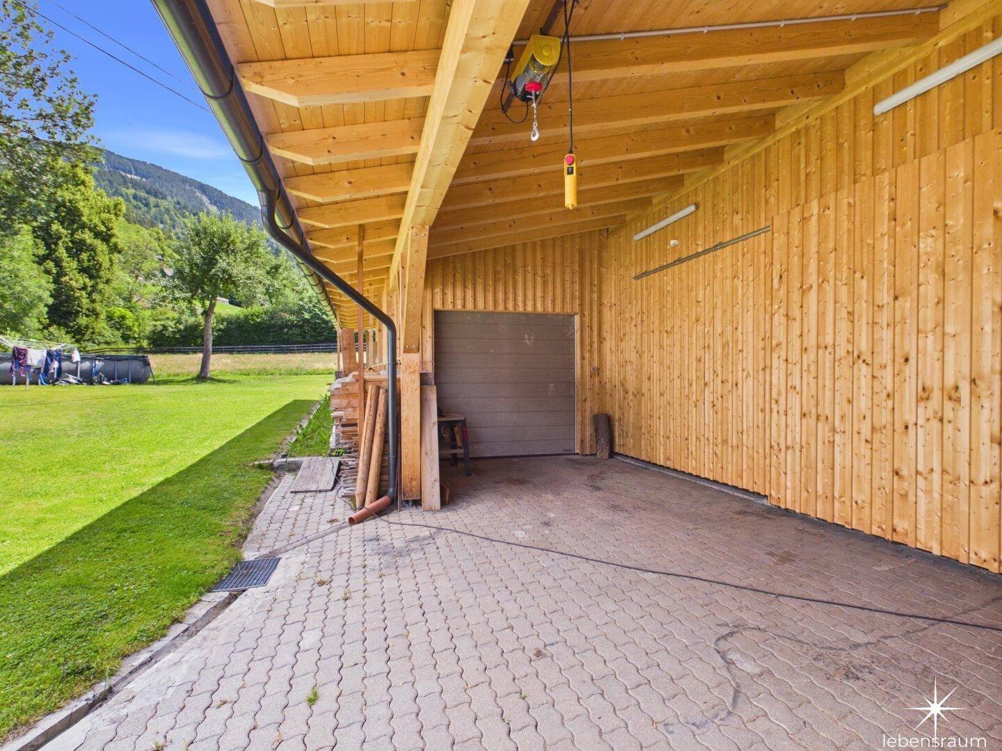 Überdachter Stellplatz oder Carport mit Holzwänden und Blick auf die Landschaft.
