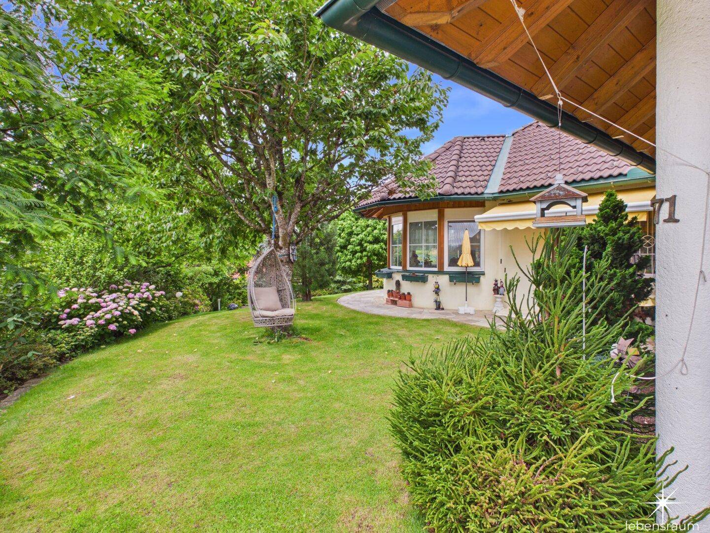 Gepflegter Gartenbereich mit Rasen, Bäumen und einer Schaukel, die zum Entspannen einlädt.