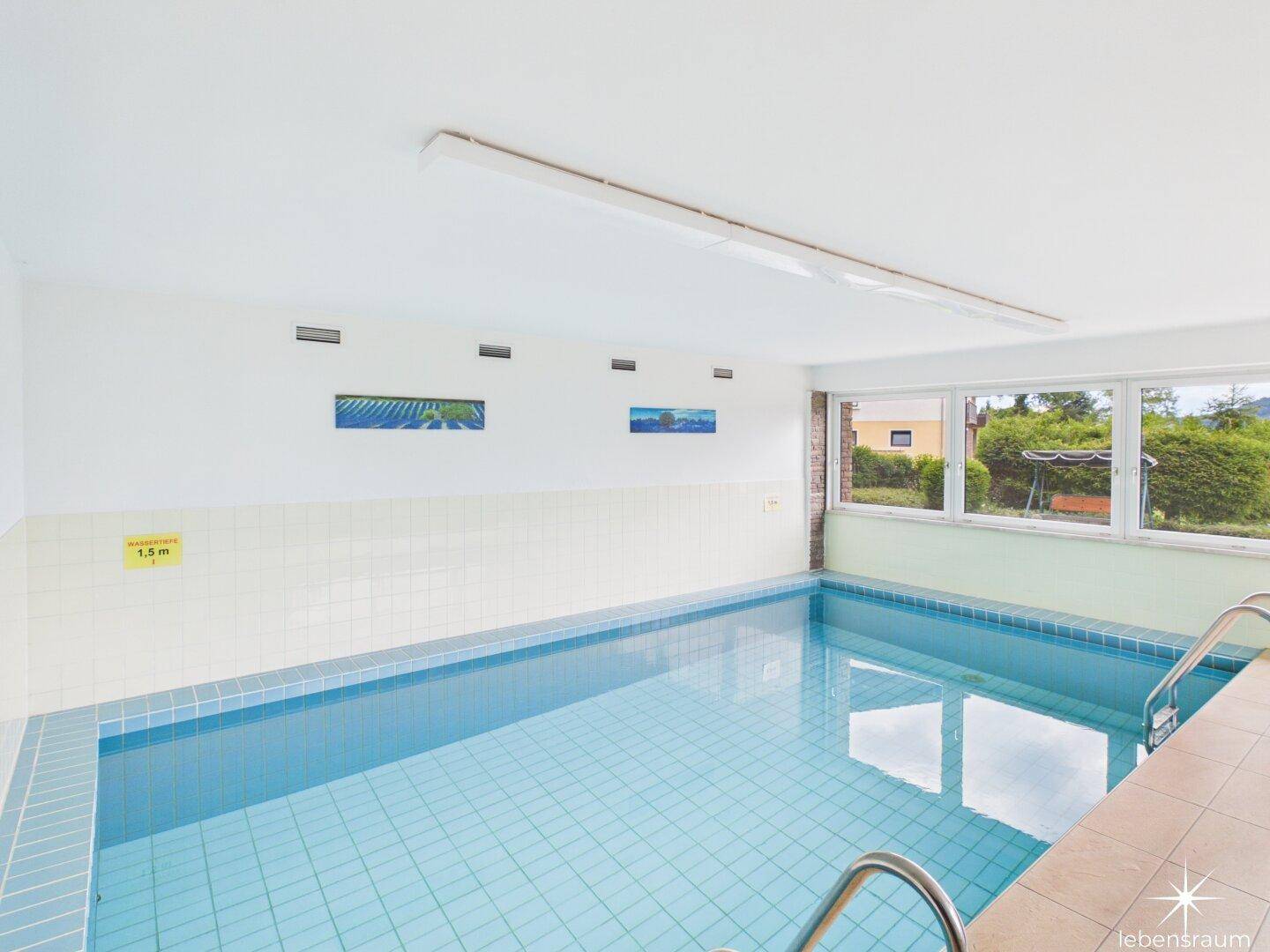 Geräumiger Innenpoolbereich mit Fliesenboden und natürlichem Lichteinfall von außen.