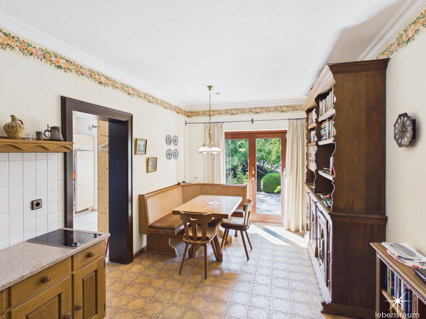 Gemütliche Wohnküche mit Holzeckbank, Fliesenboden und direktem Zugang zum Garten.