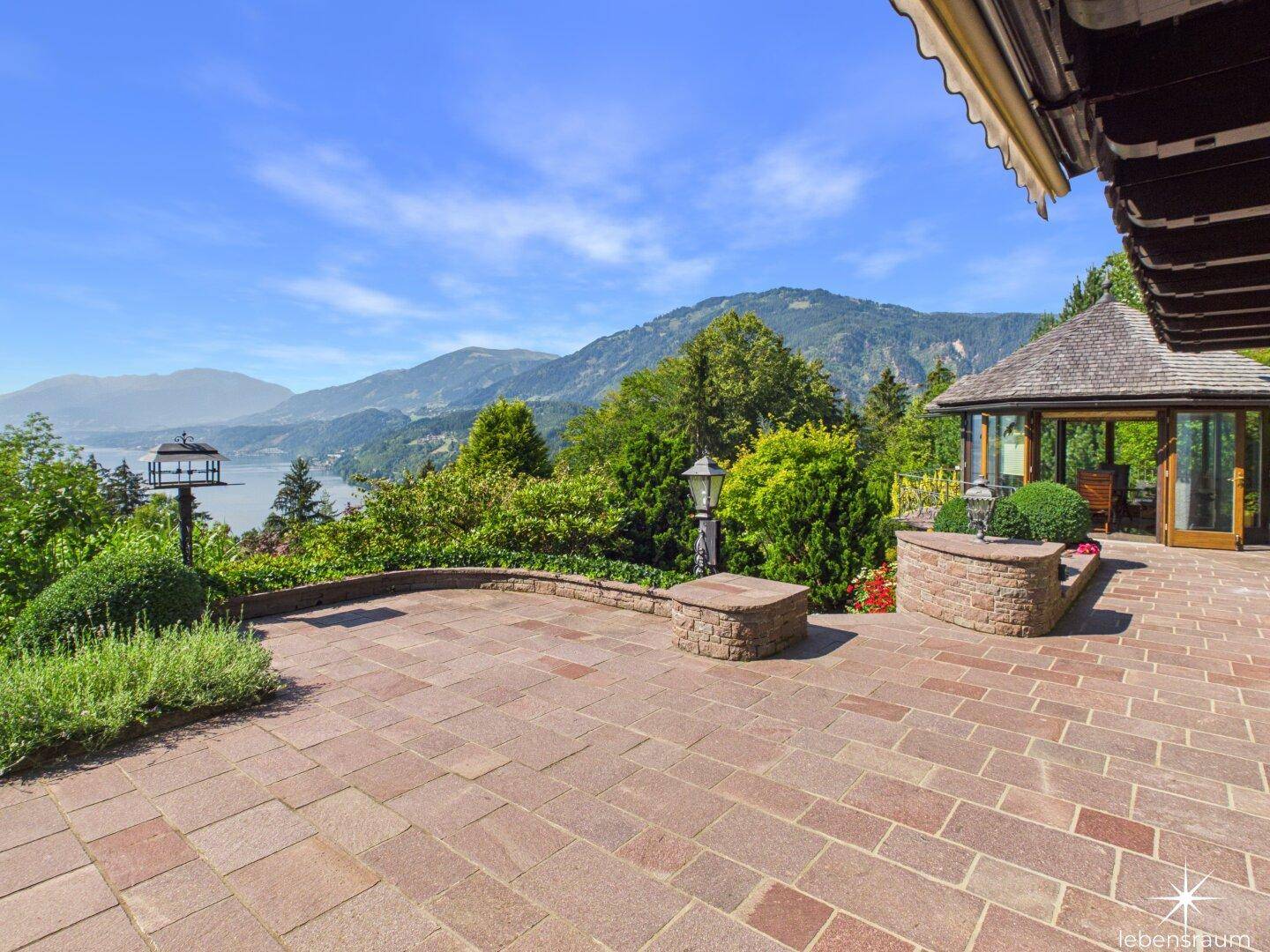 Große gepflasterte Terrasse mit Pavillon und Panoramablick auf den See und die Berge.