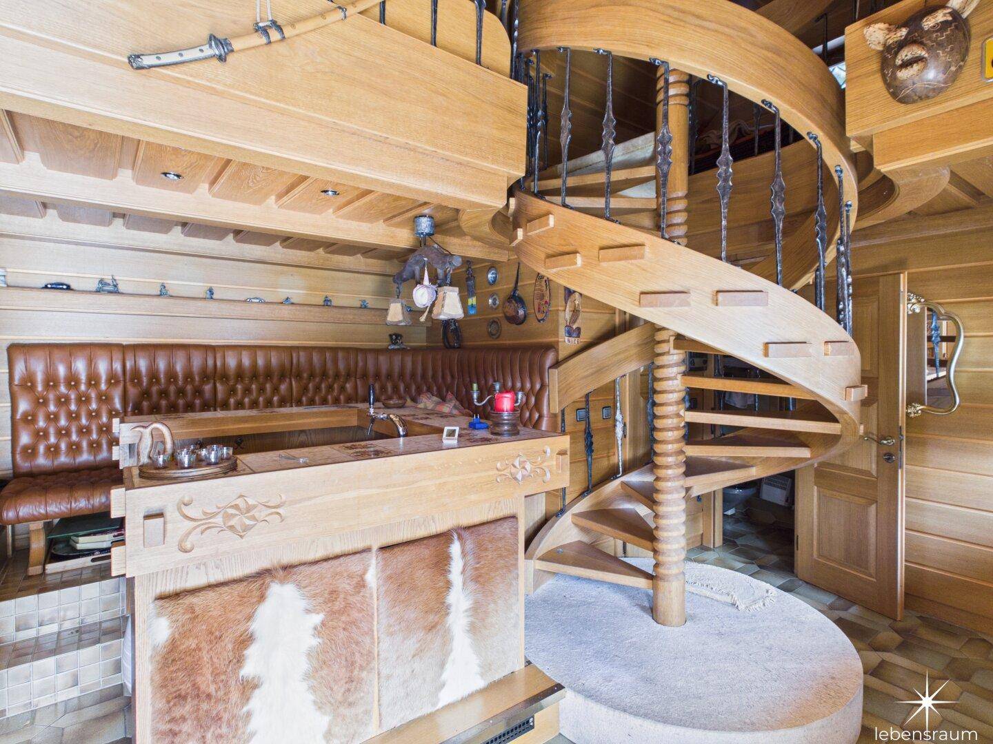 Rustikaler Innenraum mit Holzvertäfelung, Wendeltreppe und eingebauter Bar mit Ledersitzbank.