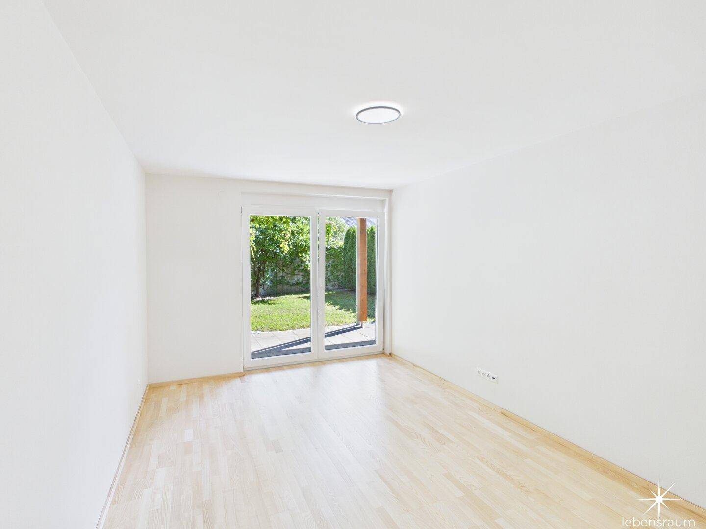 Helles Zimmer mit Holzboden und direktem Zugang zum Garten.