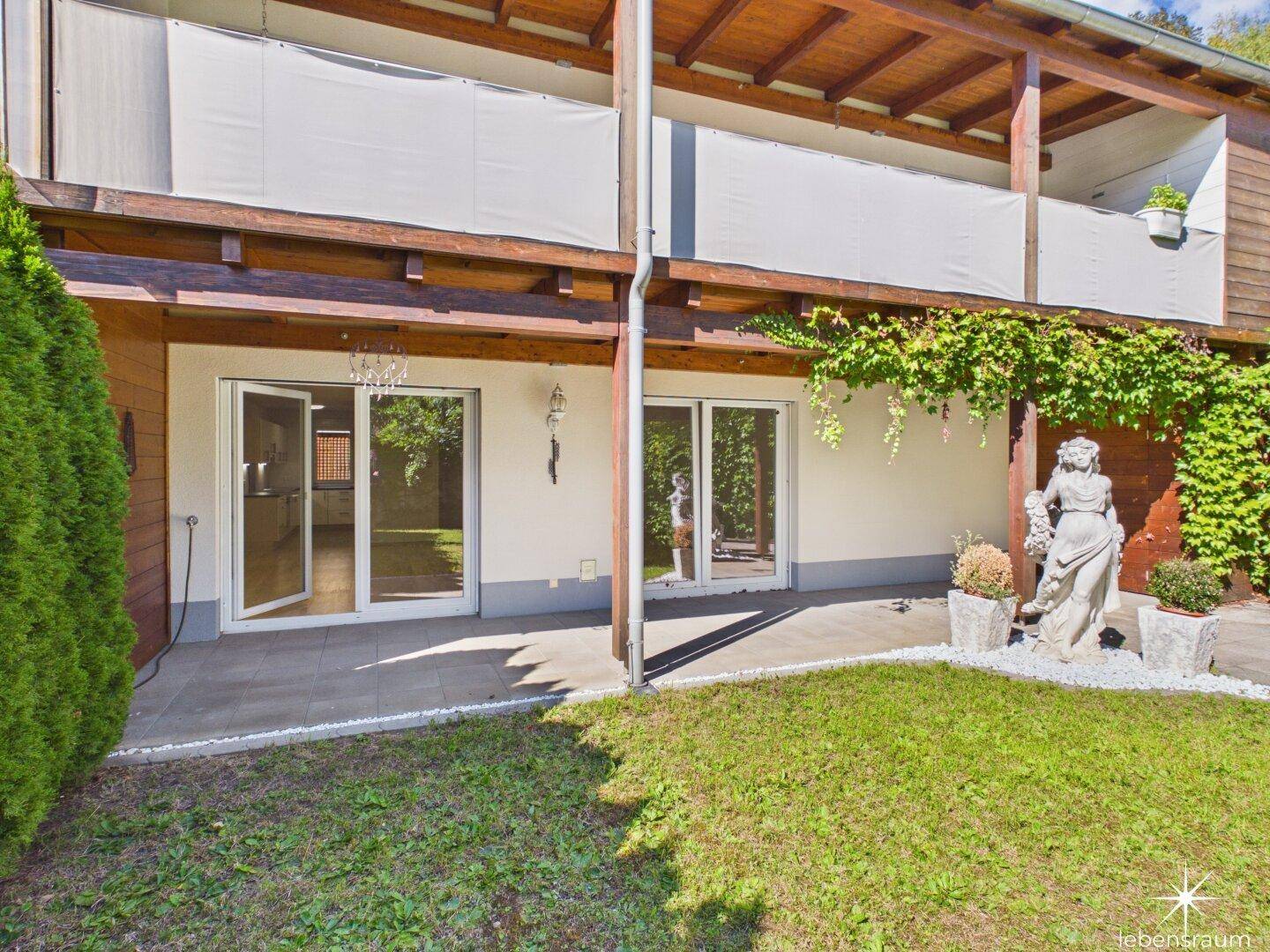 Gebäudefassade mit Terrassen und einem gepflegten Gartenbereich im Vordergrund.