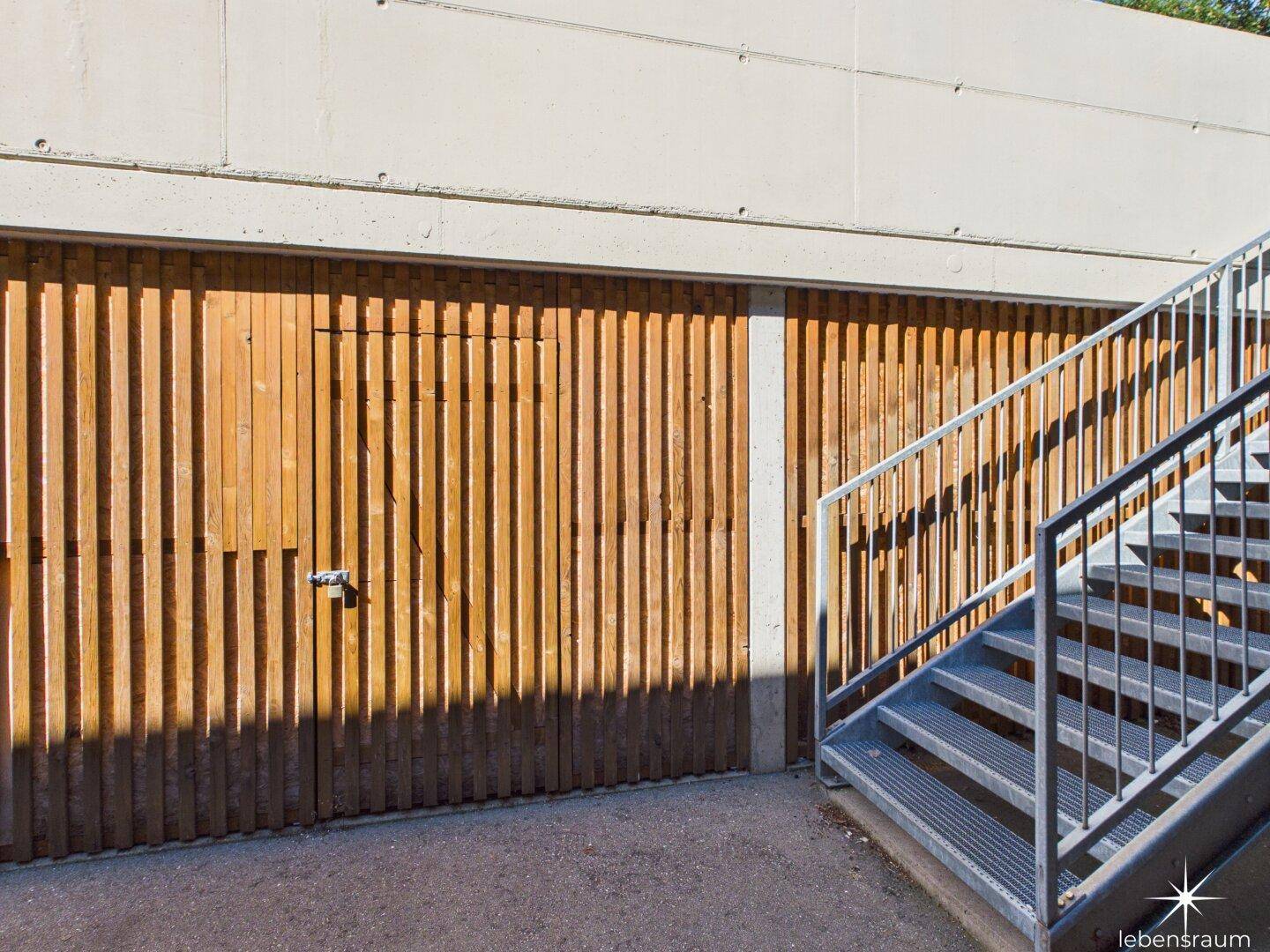 Garagenzufahrt mit Holzverkleidung und einer Außentreppe zum Gebäude.