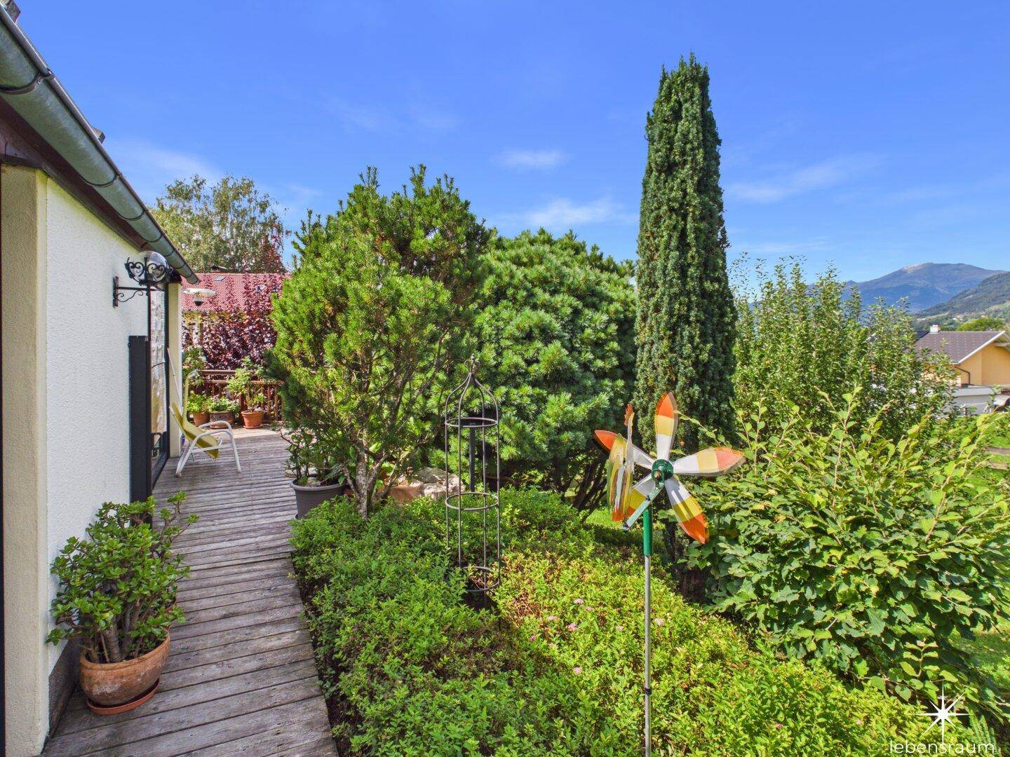 Gepflegter Gartenbereich mit Holzsteg und vielfältiger Bepflanzung, ideal zum Entspannen.