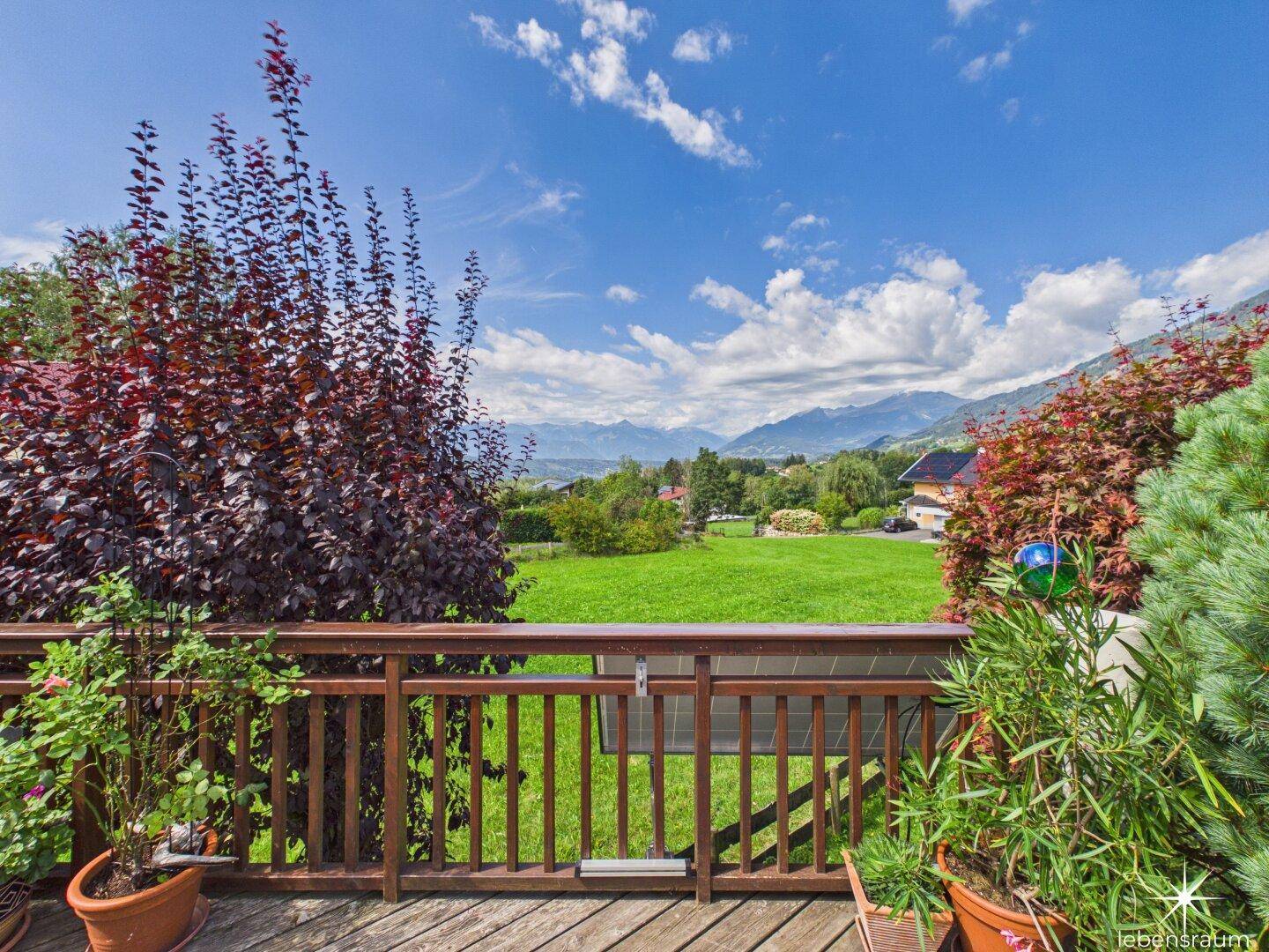 Balkon mit Holzboden und Geländer, bietet einen atemberaubenden Blick auf die Berge und Natur.