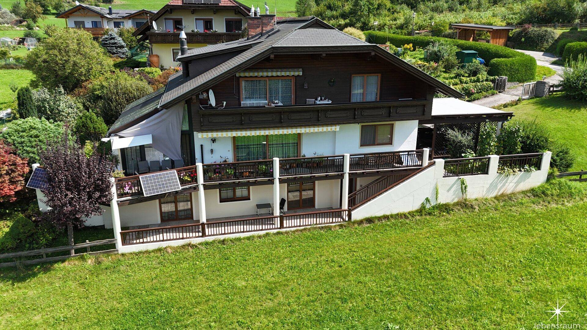 Luftaufnahme des Hauses mit großem Grundstück, umgeben von grünen Wiesen und Bergen.