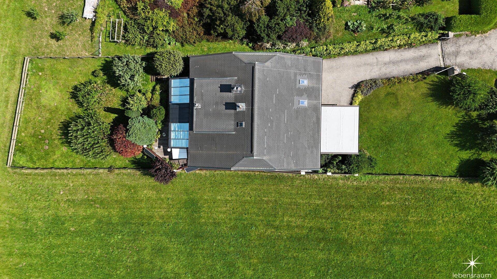 Senkrechte Luftaufnahme des Hauses mit Dach, Garten und angrenzender Zufahrt.