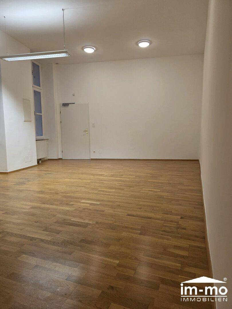 Leerer Raum mit Holzboden und schlichter Deckenbeleuchtung, bereit für individuelle Gestaltung.