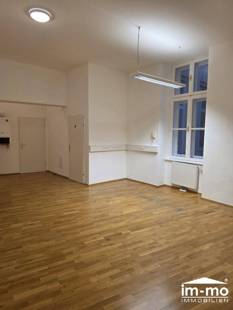 Heller Büroraum mit Holzboden und großen Fenstern, bietet eine angenehme Arbeitsatmosphäre.