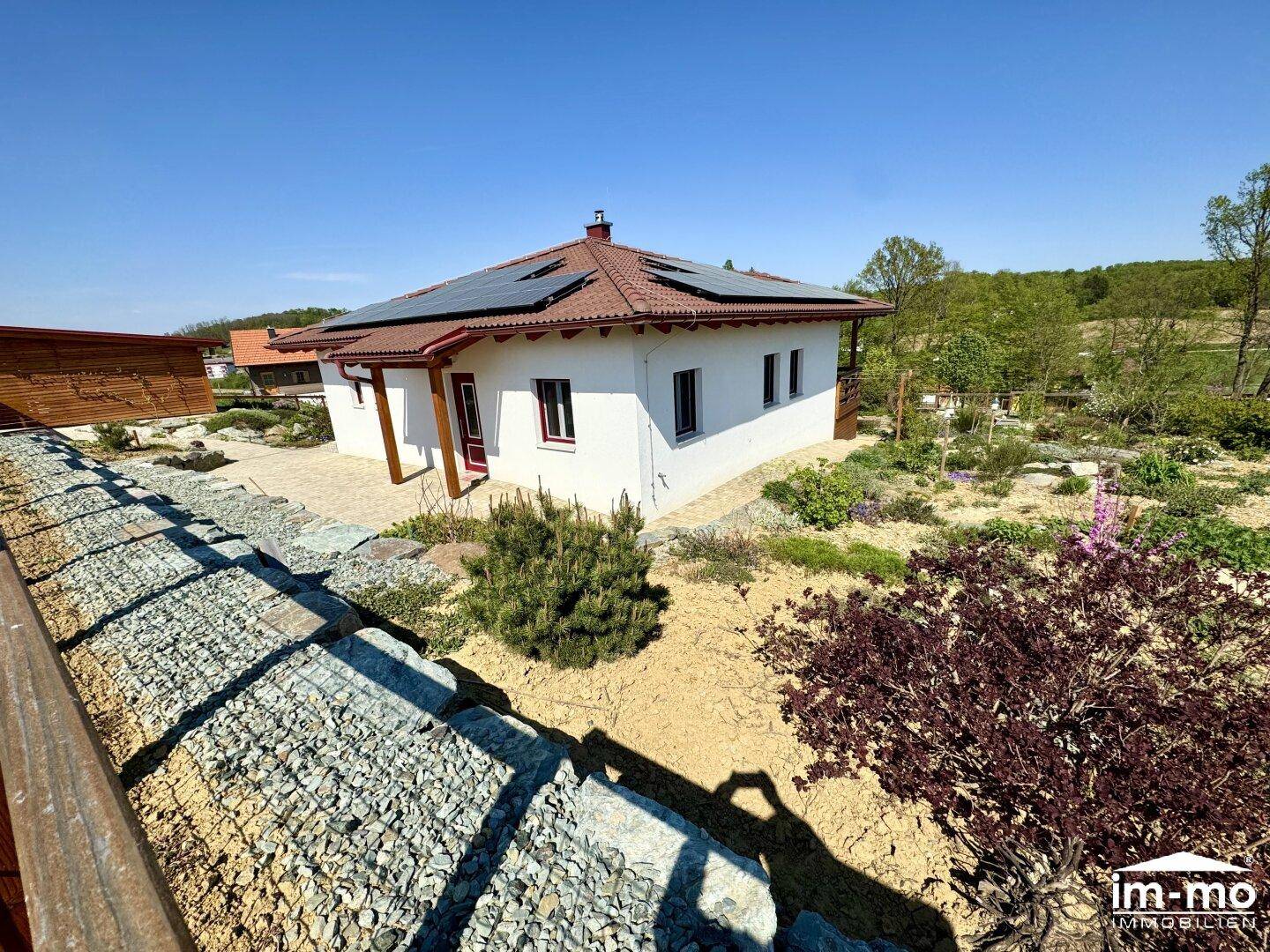 Einfamilienhaus mit Photovoltaikanlage auf dem Dach und weitläufigem Gartenbereich.