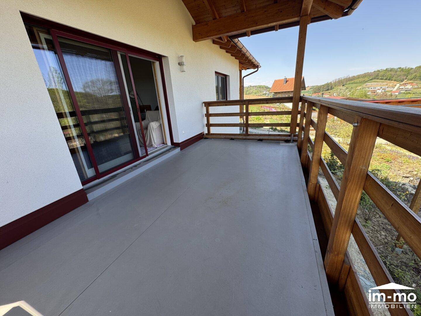Geräumiger Balkon mit Holzbalken und weitem Blick in die Landschaft.