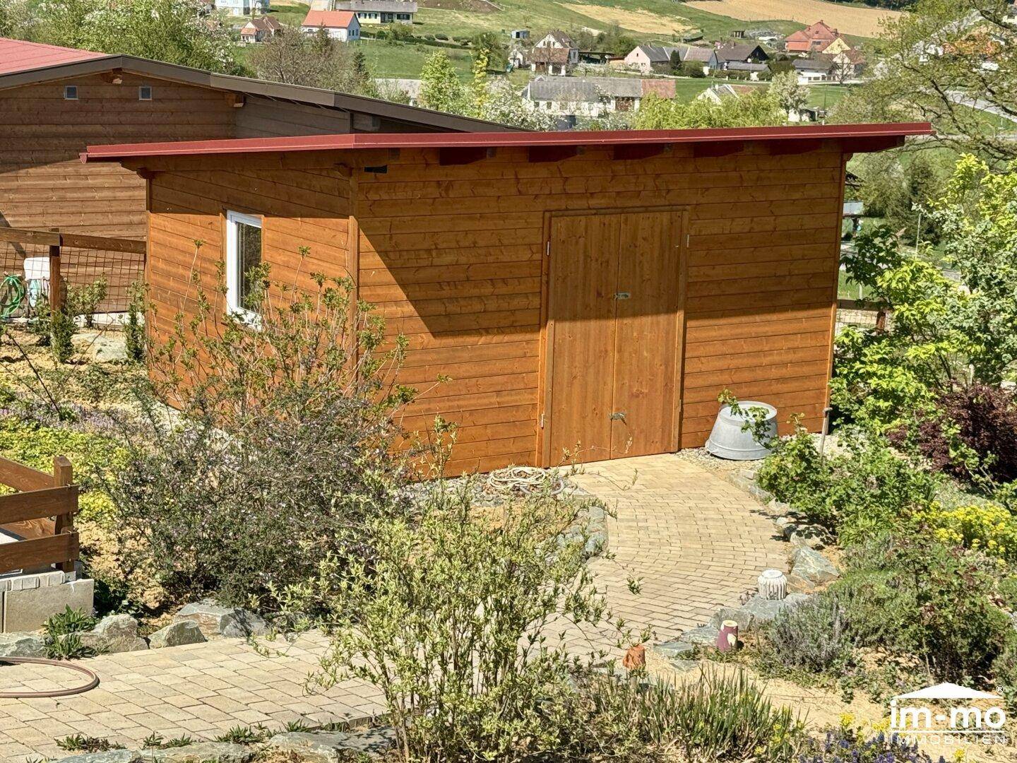 Hölzernes Gartenhaus in einem gepflegten Garten mit Steinweg.