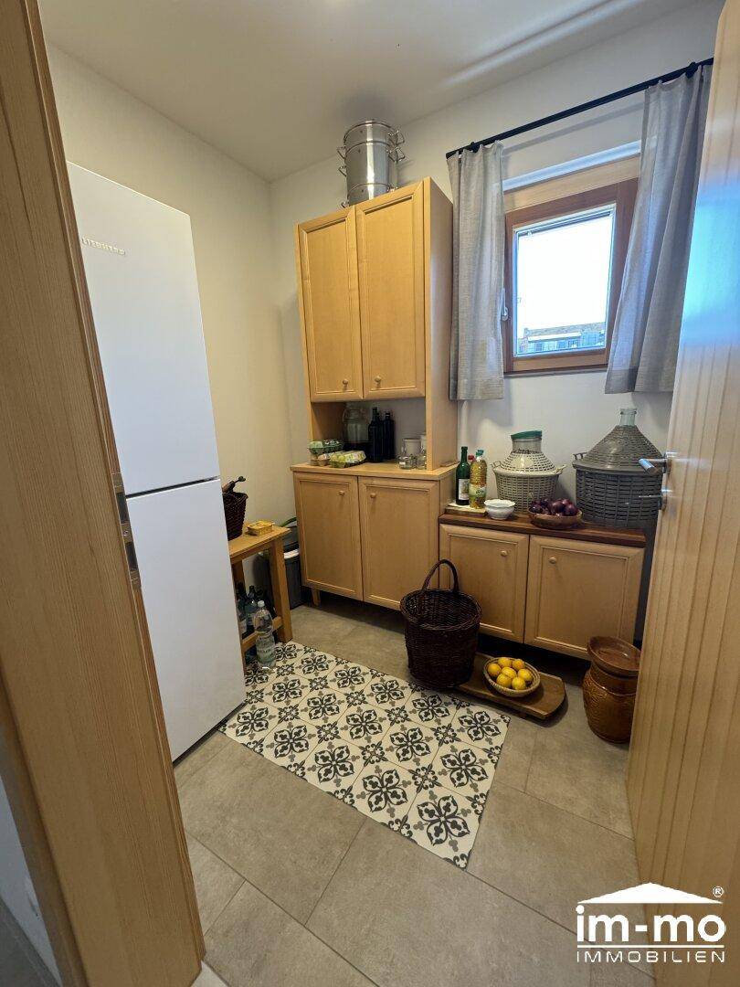 Praktische Speisekammer mit Regalen, Kühlschrank und Fenster.