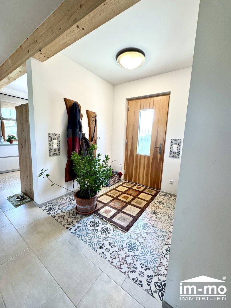 Eingangsbereich mit dekorativen Fliesen, Garderobe und Holztür.