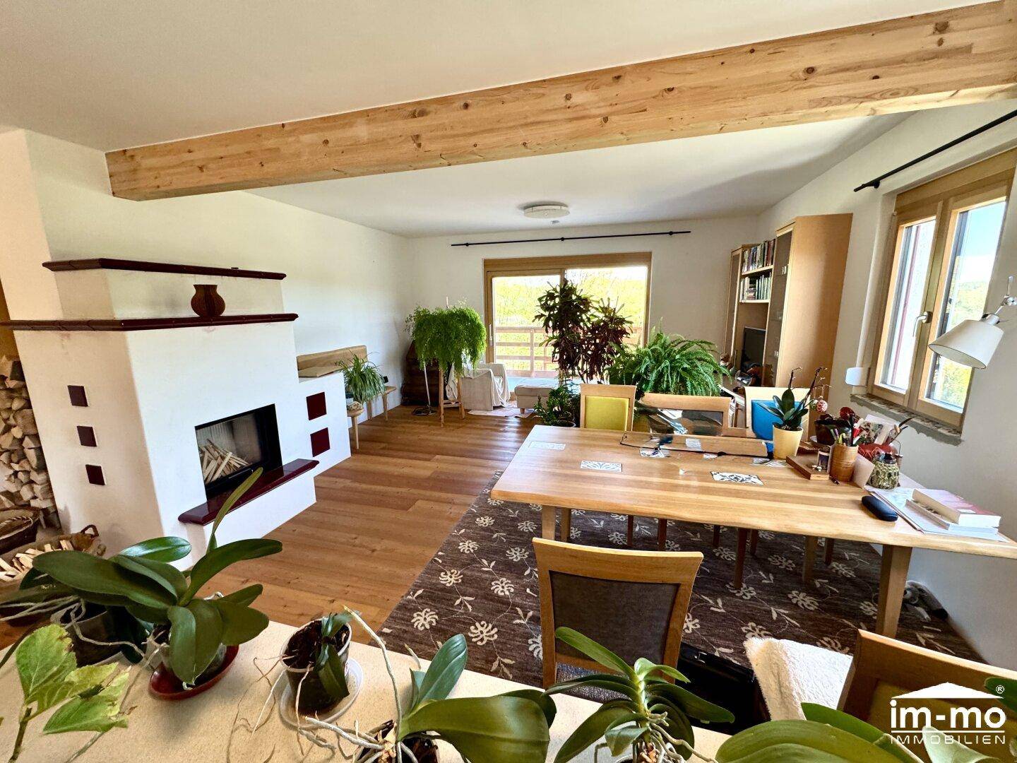 Gemütliches Wohnzimmer mit Kamin, Holzbalken und Blick ins Grüne.