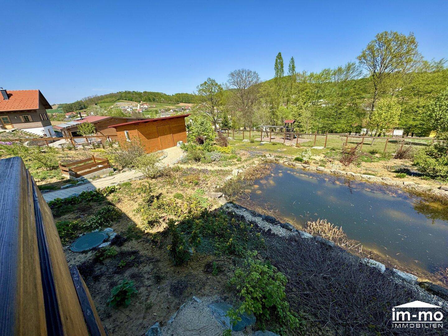 Weitläufiger Gartenbereich mit Teich, Spielplatz und viel Grünfläche.