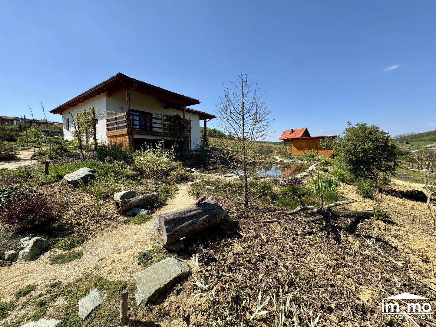 Haus mit naturnahem Garten, Teich und Blick auf die umliegende Landschaft.