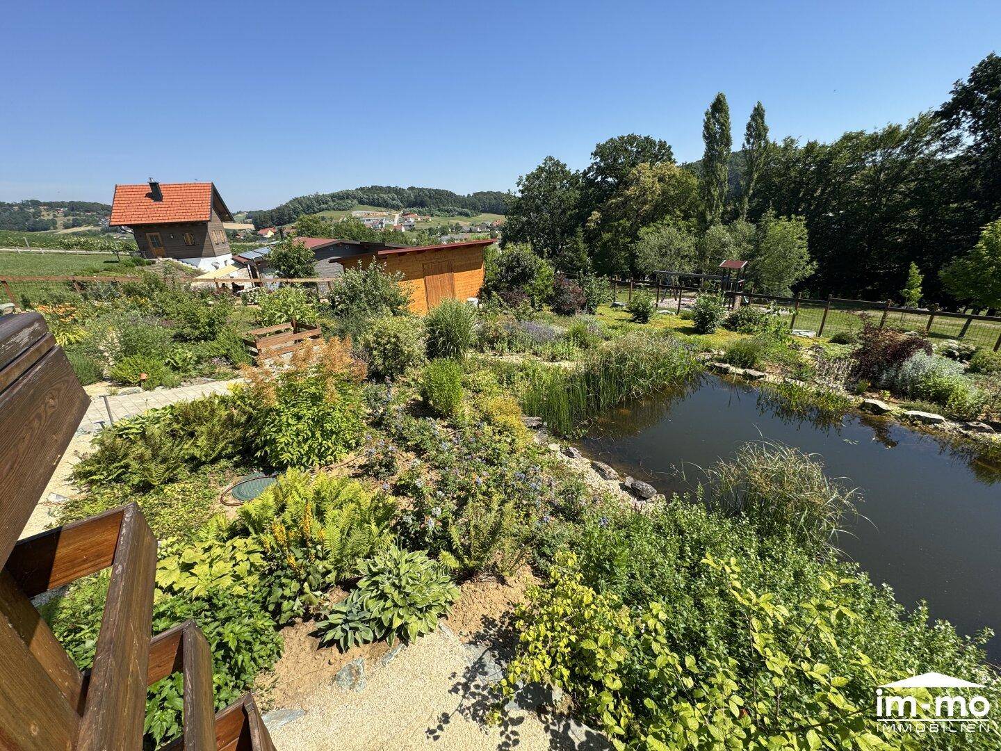 Weitläufiger Garten mit Biotop, üppiger Bepflanzung und ländlichem Ausblick in die Natur.