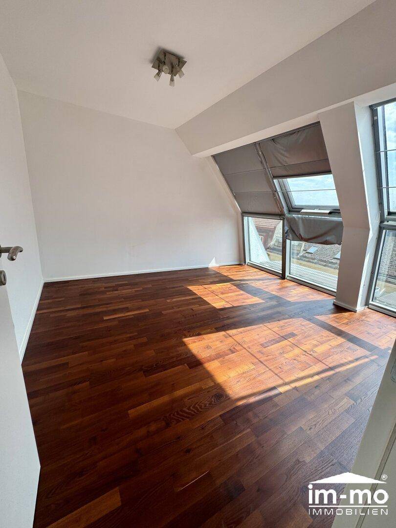 Geräumiges Schlafzimmer mit dunklem Parkettboden und großen Dachfenstern, bietet viel Helligkeit.