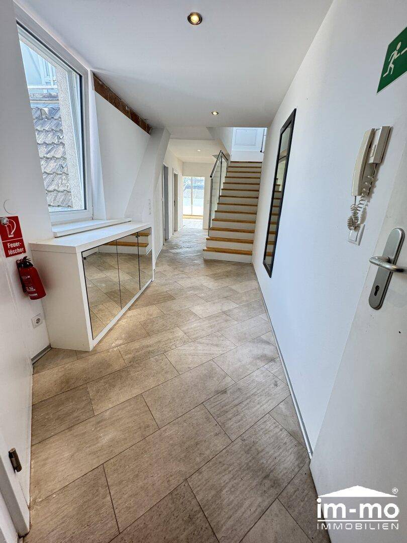 Heller Flur mit Fliesenboden, Spiegelschrank und Treppenaufgang, führt zu weiteren Räumen.