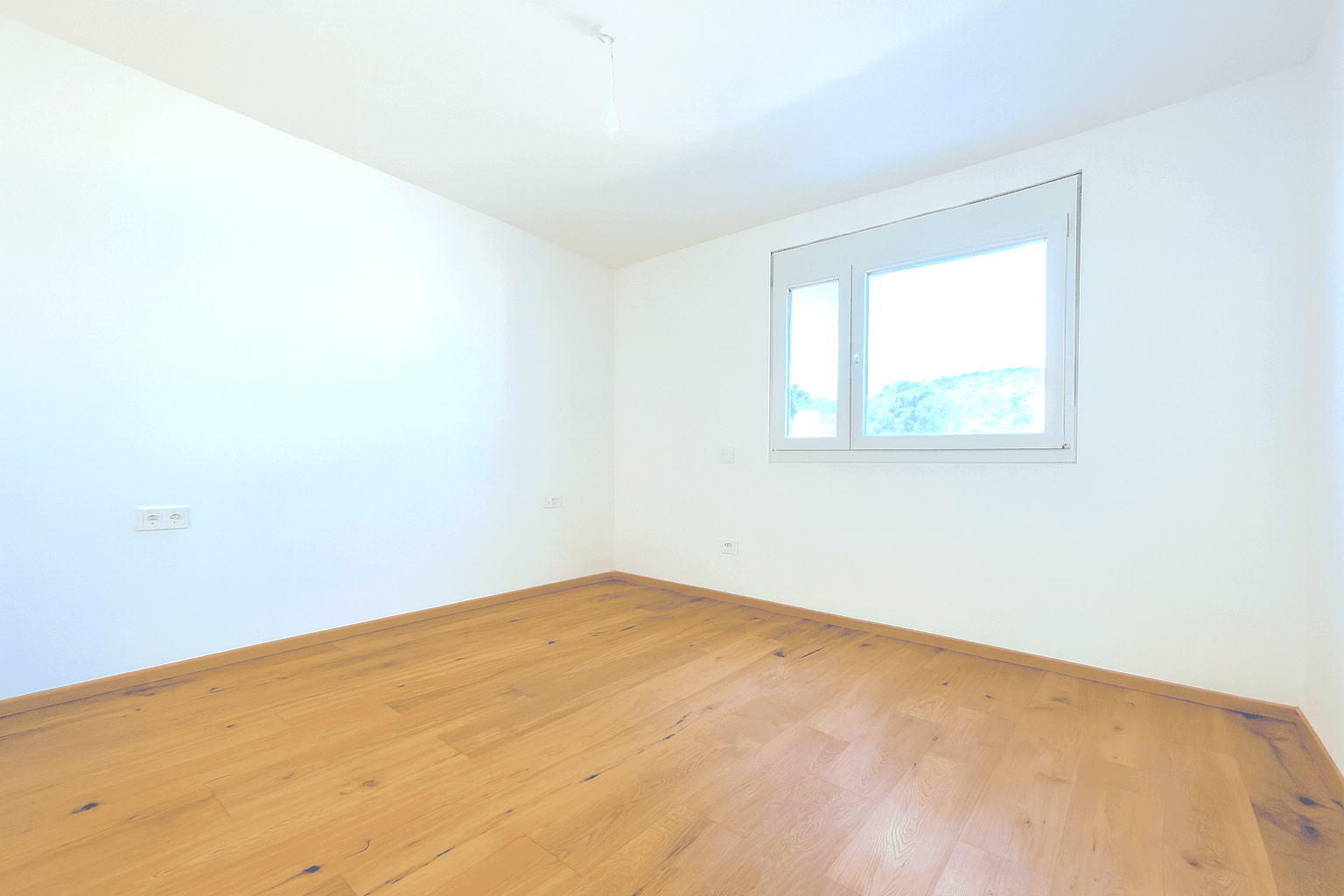 Geräumiger, heller Wohnbereich mit Holzboden und Zugang zum Eingangsbereich, bereit zur Gestaltung.