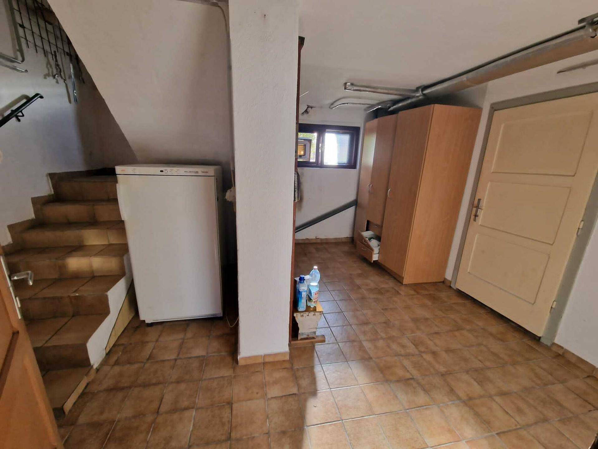 Kellerbereich mit gefliestem Boden, Treppe und praktischen Lagerschränken.