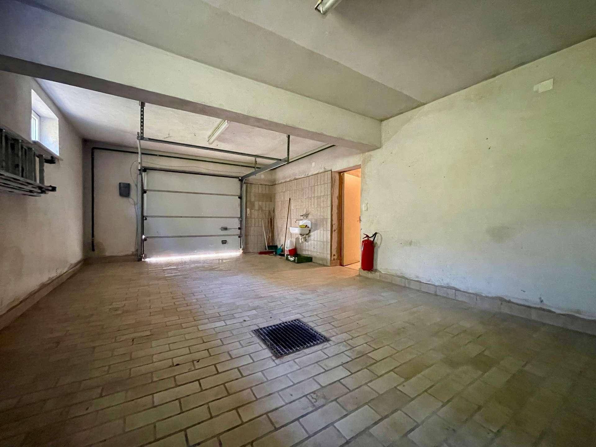 Geräumige Garage mit Rolltor, Fliesenboden und direktem Zugang zum Haus.