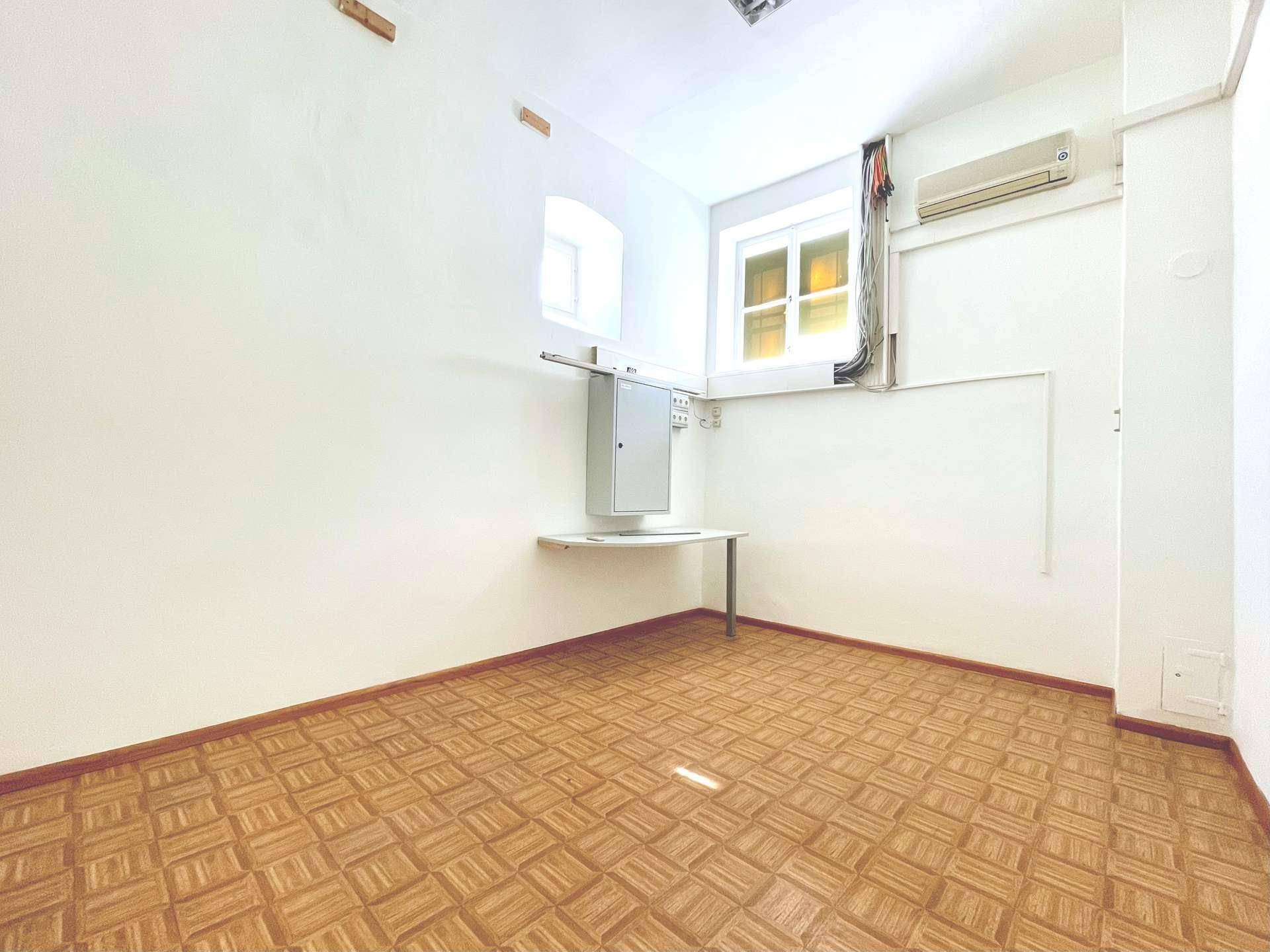 Kleinerer Büroraum mit Fenster, Klimaanlage und einem praktischen Wandtisch.