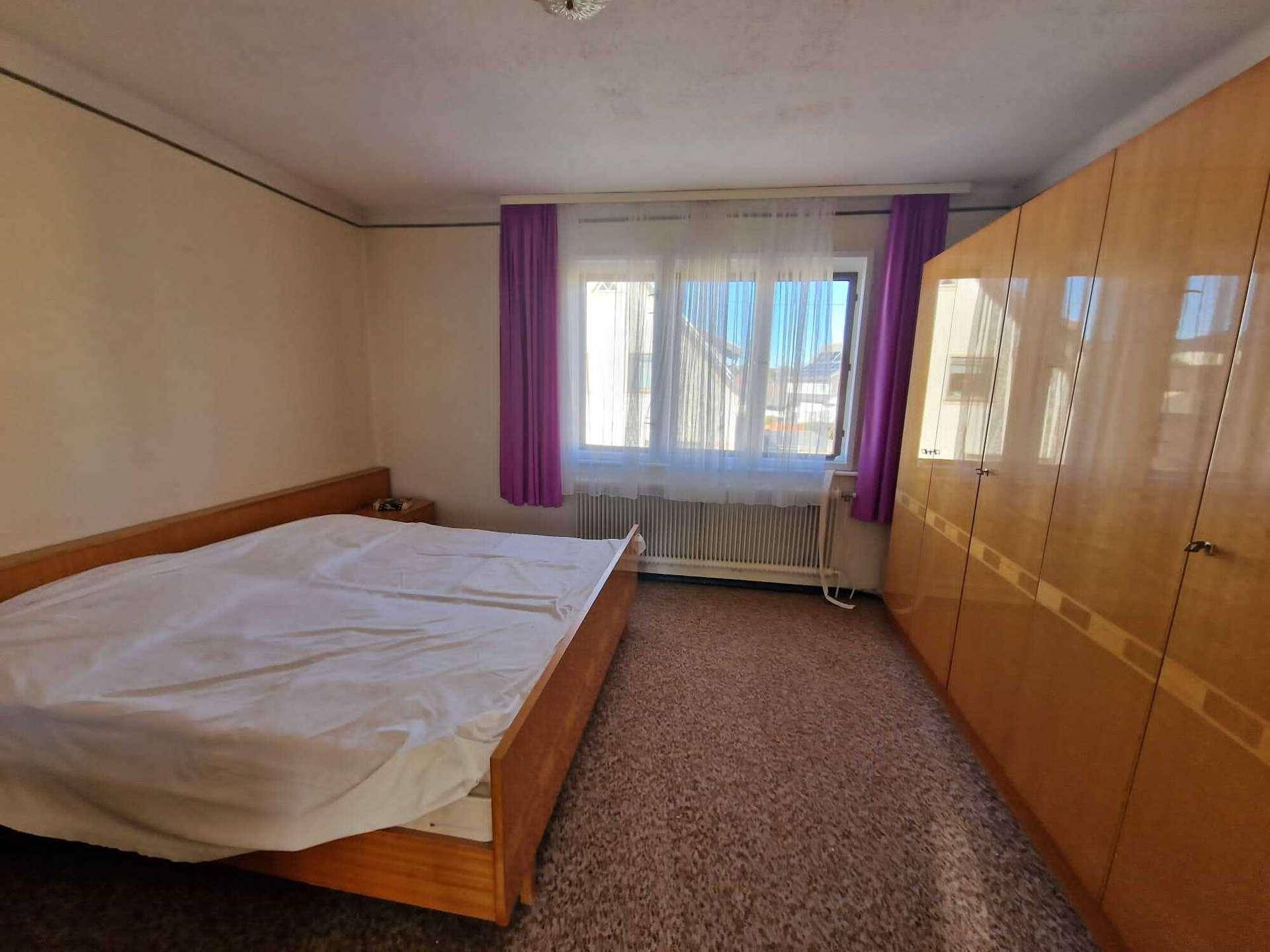 Gemütliches Schlafzimmer mit Doppelbett, großem Kleiderschrank und Teppichboden.