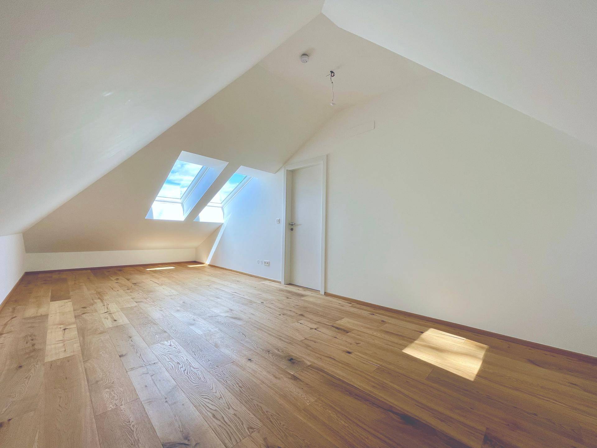 Helles Wohnzimmer im Dachgeschoss mit Holzboden und Dachfenstern, bietet eine angenehme Wohnatmosphäre.