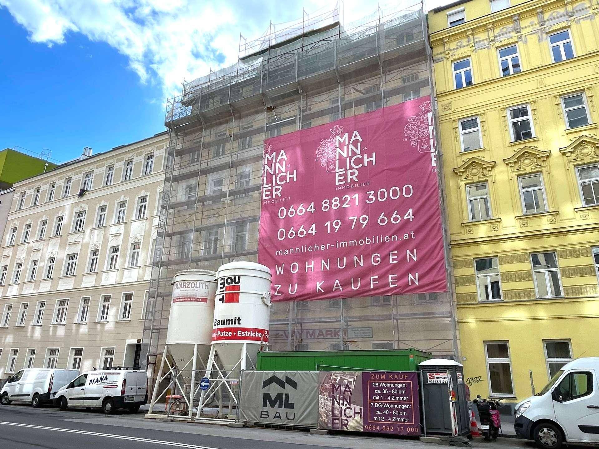 Gebäude unter Gerüst mit einem großen Werbebanner für Wohnungen zum Verkauf in der Stadt.