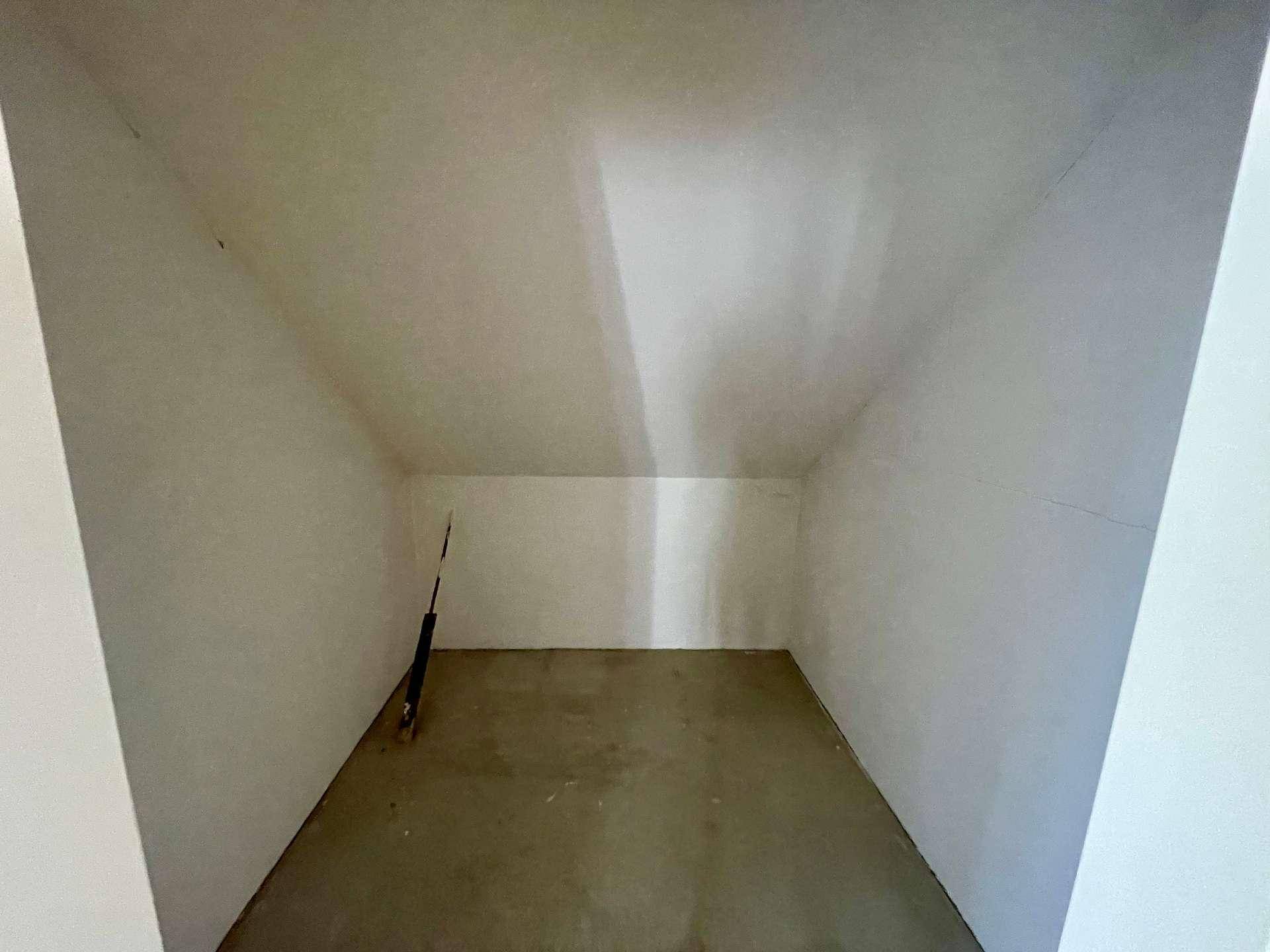 Leerer Abstellraum im Dachgeschoss mit schrägen Wänden, ideal für Lagerung.