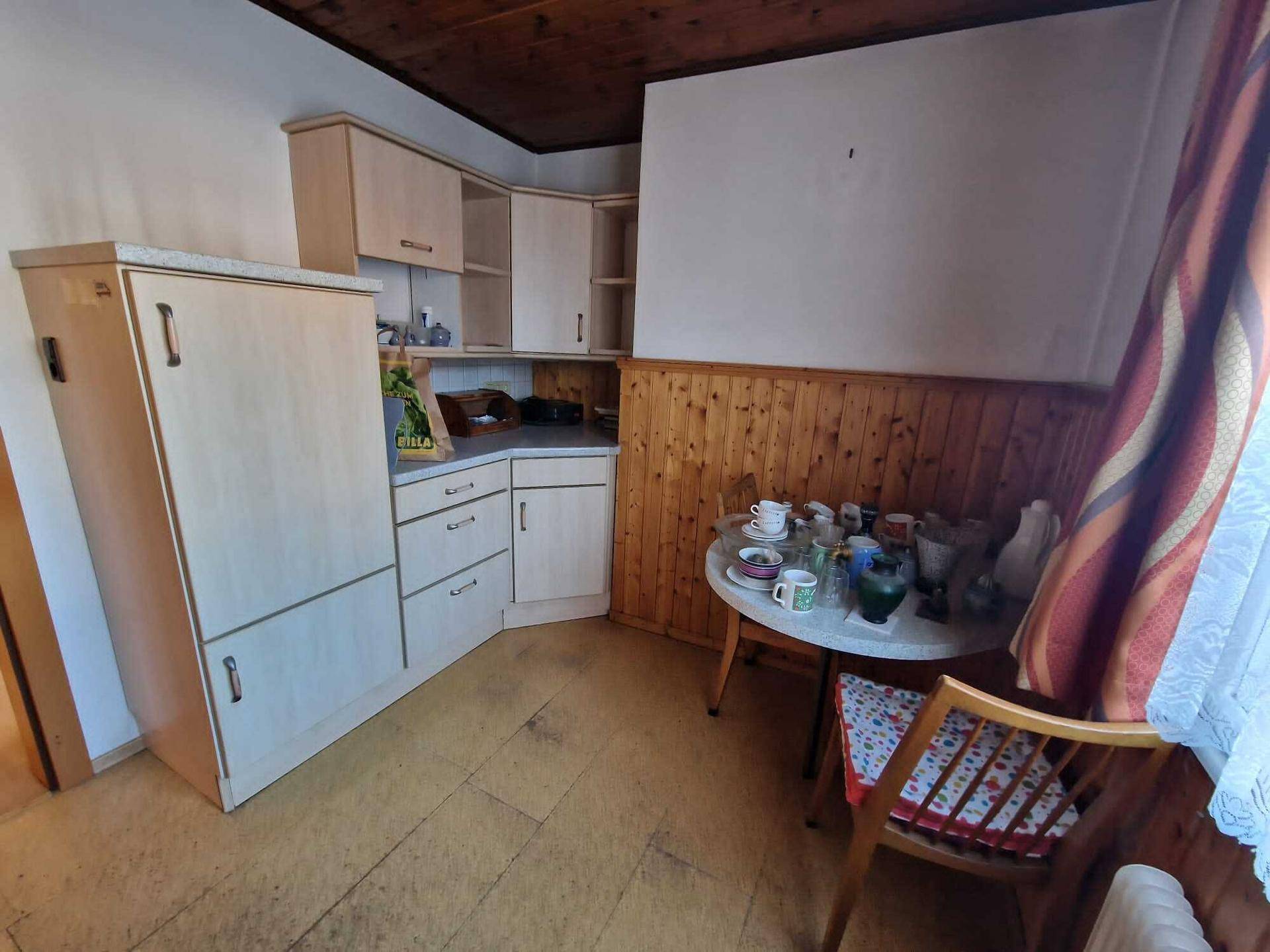 Kleine Küche mit Holzdecke, Einbauschränken und einem Esstisch.