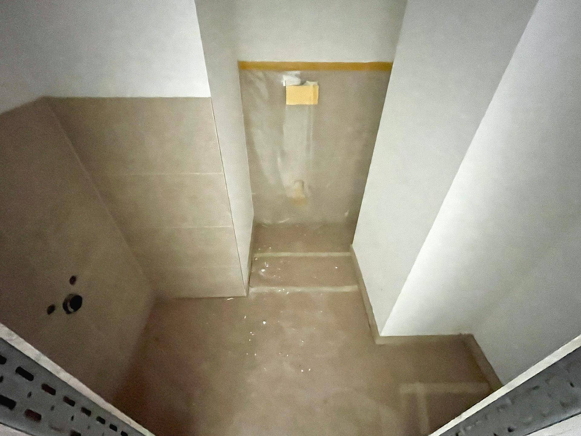 Badezimmer im Rohbau mit vorbereiteten Anschlüssen und schrägen Wänden, bereit für die Installation.