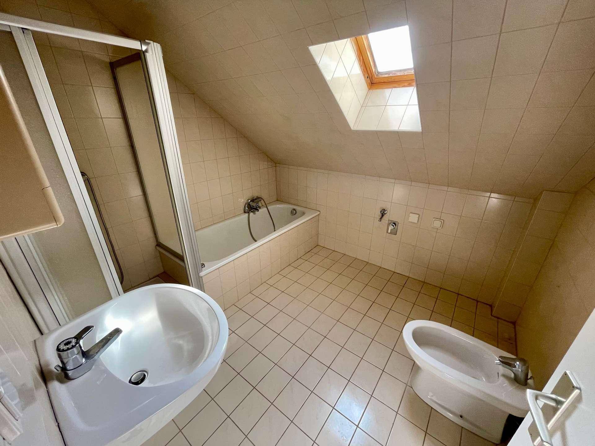 Badezimmer im Dachgeschoss mit Badewanne, Duschkabine, Bidet und Dachfenster.