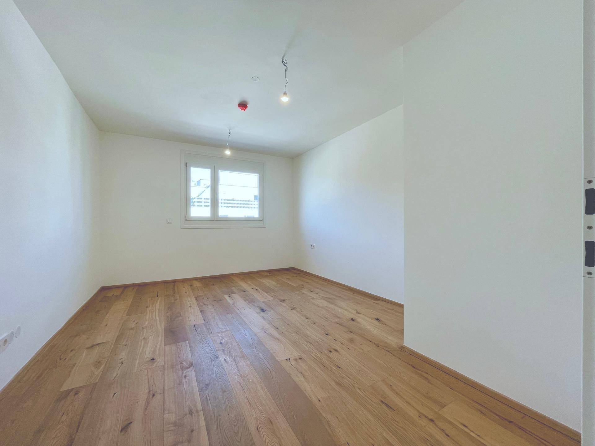 Helles Schlafzimmer mit Holzboden und Fenster, bietet eine ruhige und angenehme Atmosphäre.