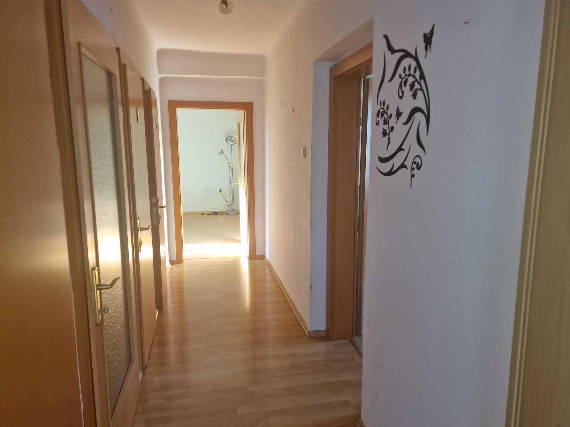 Heller Flur mit Laminatboden und mehreren Türen, die zu verschiedenen Räumen führen.