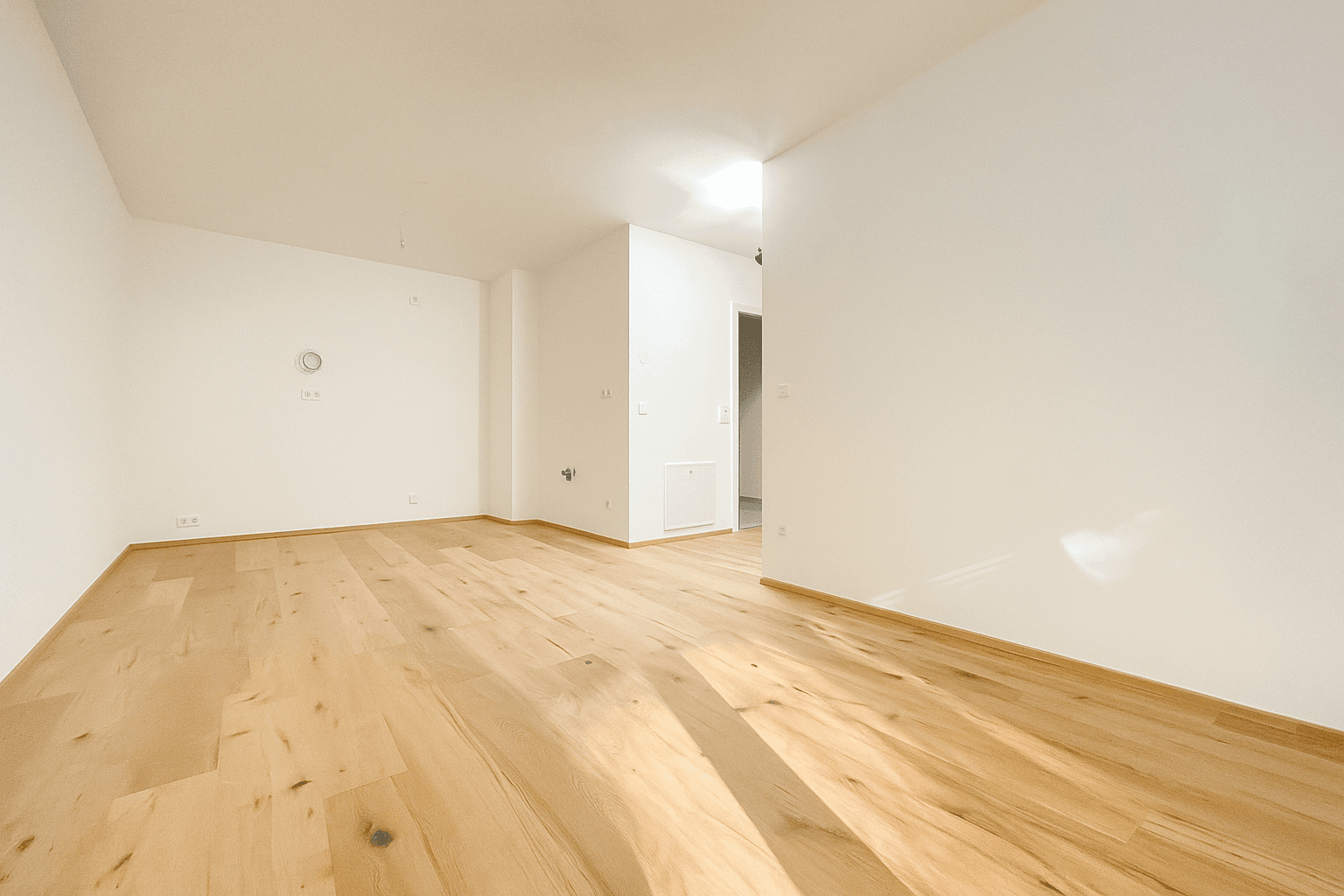 Geräumiger, heller Raum mit Holzboden und viel Tageslicht, bereit zur Einrichtung.