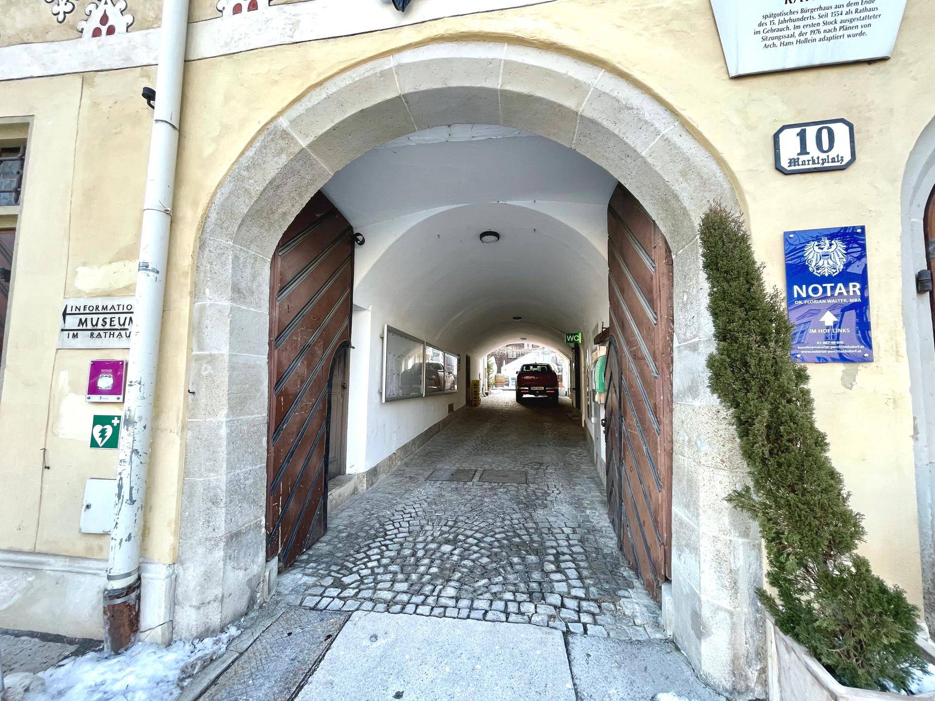 Historischer Torbogen mit Kopfsteinpflaster-Durchfahrt und Holztoren in einer traditionellen Altstadtgasse.