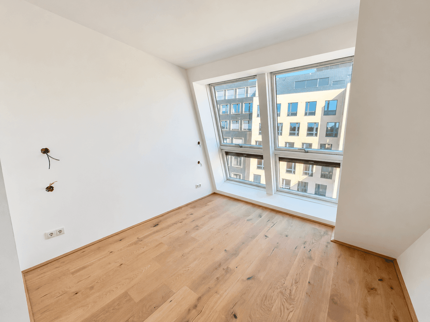 Geräumiges Zimmer mit Eichenparkett und viel Tageslicht durch die großen Fenster.