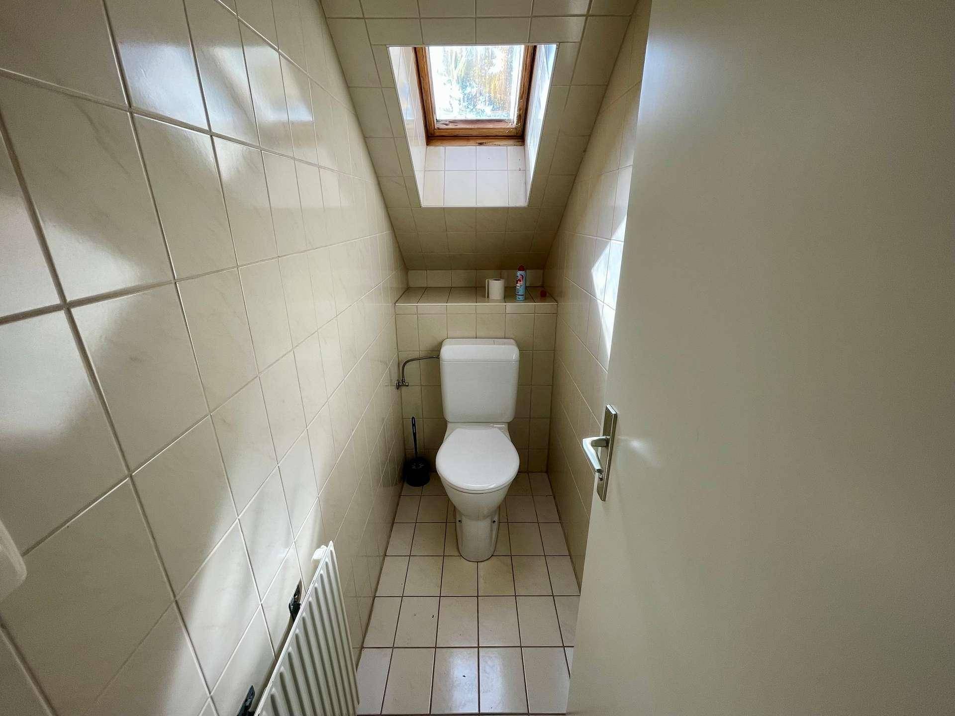 Separates WC im Dachgeschoss mit Fliesenboden und Dachfenster.
