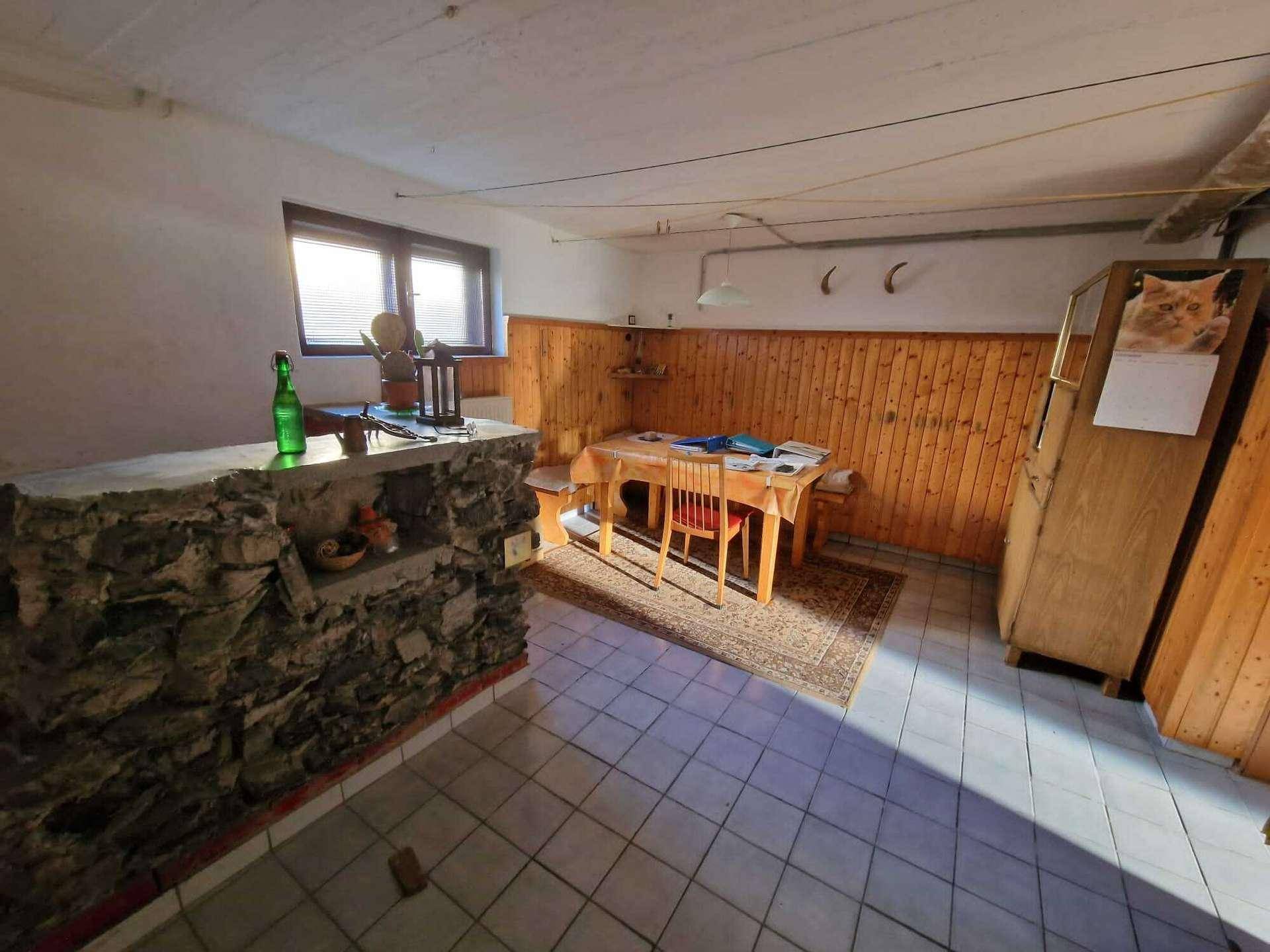 Rustikaler Kellerraum mit Holztäfelung, gefliestem Boden und einem gemauerten Bartresen.