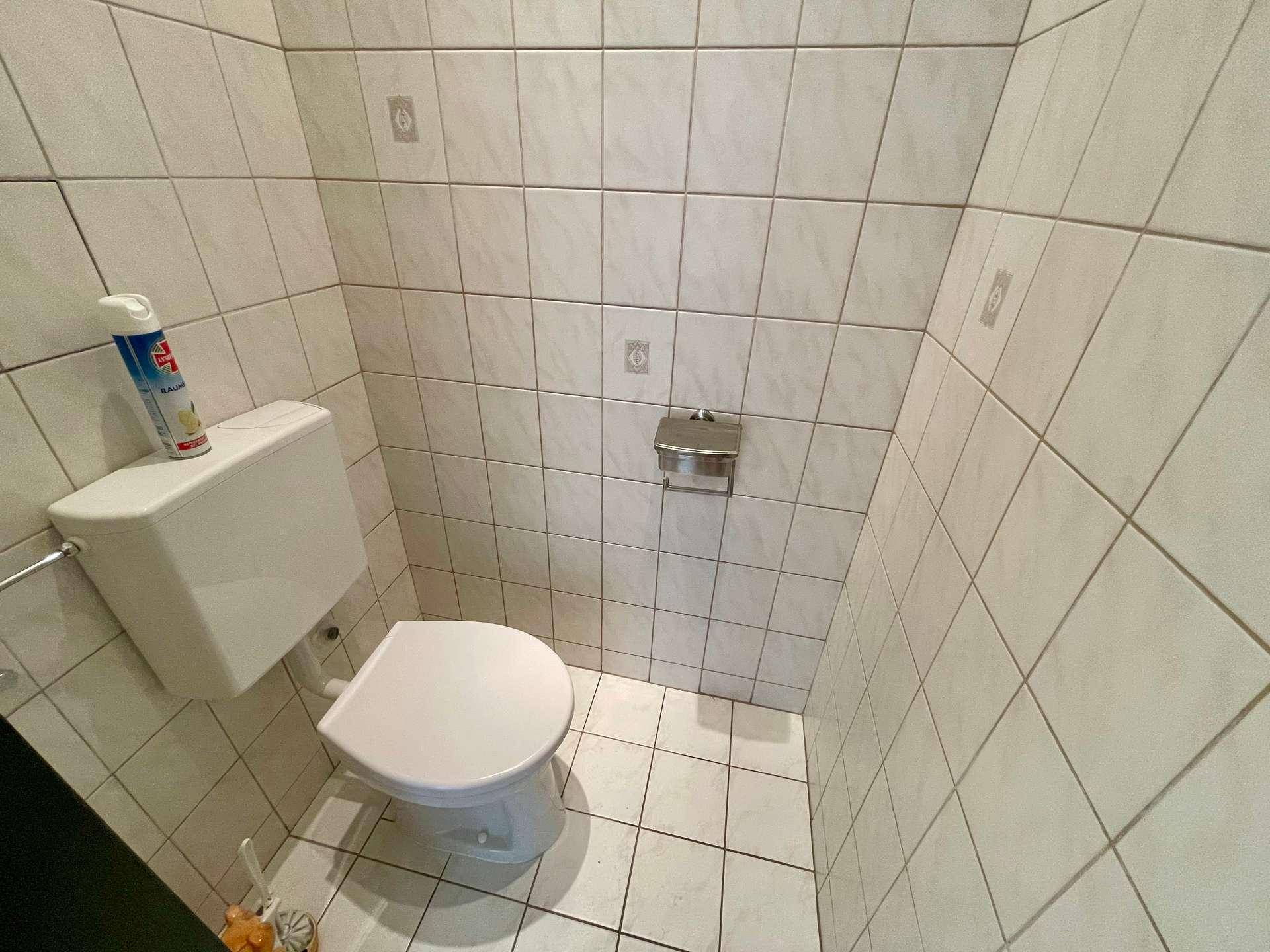Kleines separates WC mit Fliesen an Wänden und Boden, funktional und sauber.